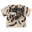 Rebel Minds cream tapestry t-shirt with a large graphic of a skull with wings and the word "Conquer" in gothic font, adorned with feathers and rhinestones.