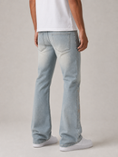 A person shown from the back wearing light-wash blue jeans, a white t-shirt, and white sneakers against a plain light gray studio background.